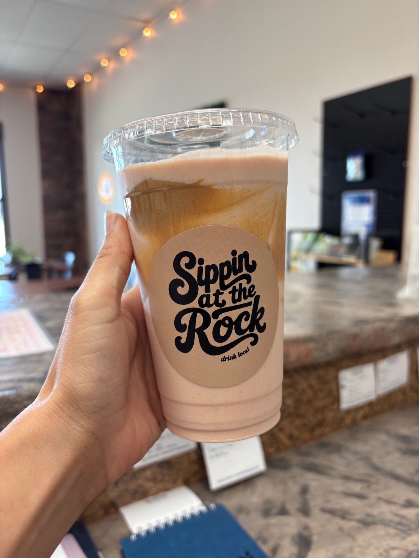 A protein shake with a Sippin at the Rock sticker on the cup